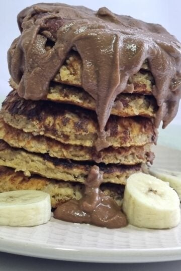 picture of a stack of pancakes decorated with chocolate and banana slices.