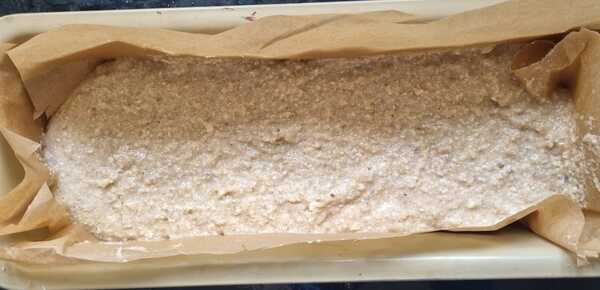 Picture banana bread batter being poured into a lined loaf pan.