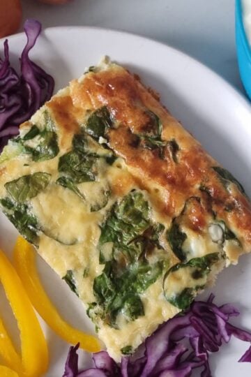 High protein egg bake on a plate accompanied with vegetables.