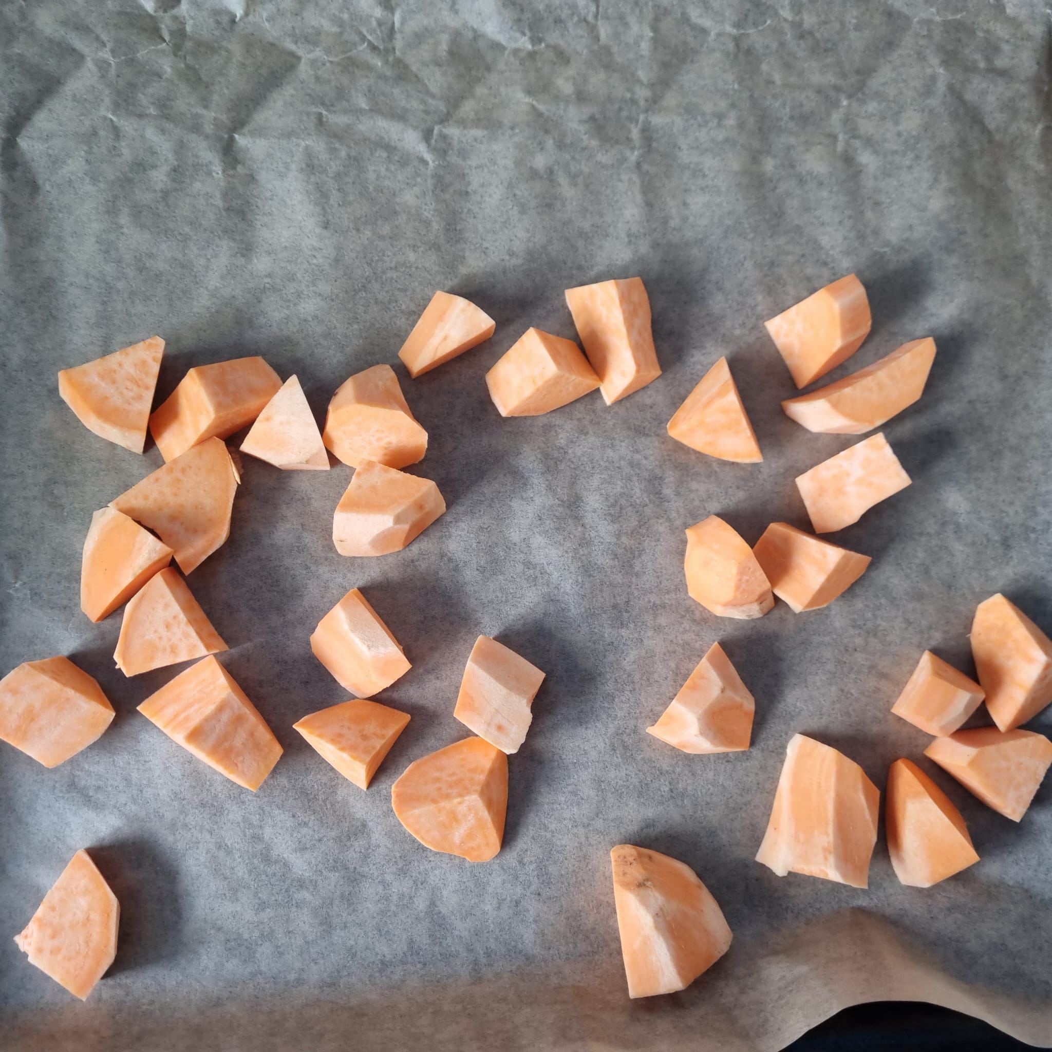 Lined baking sheet with cubed sweet potatoes ready to be baked.