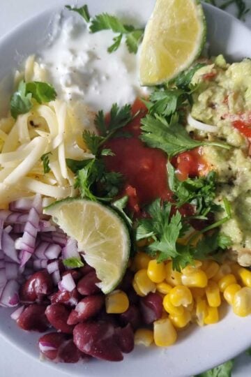 A bowl of cottage cheese taco bowl garnished with cilantro and lime wedges.