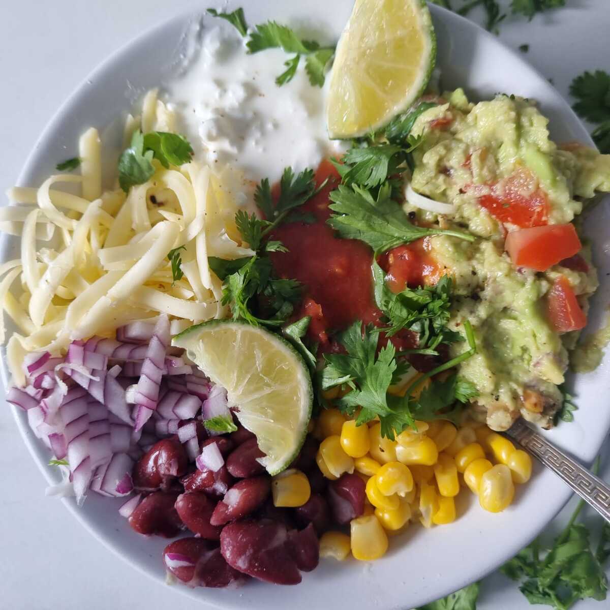 A bowl of cottage cheese taco bowl garnished with cilantro and lime wedges.