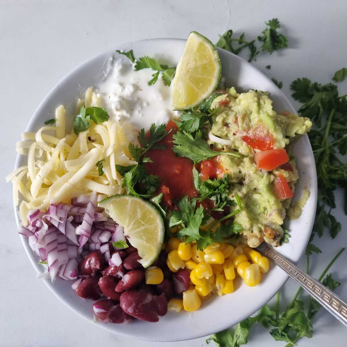 A bowl of cottage cheese taco bowl garnished with cilantro and lime wedges.
