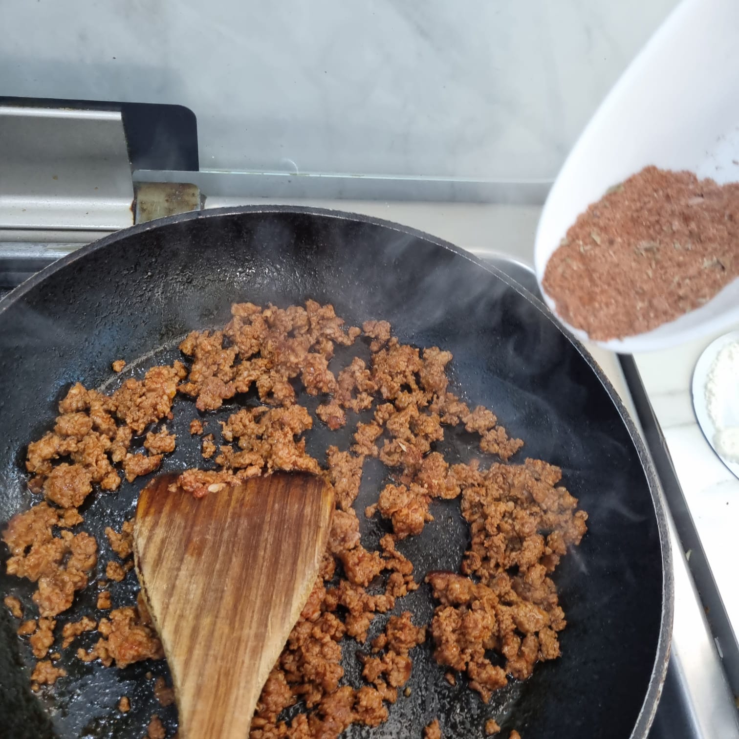 Adding taco seasoning to the fried beef.