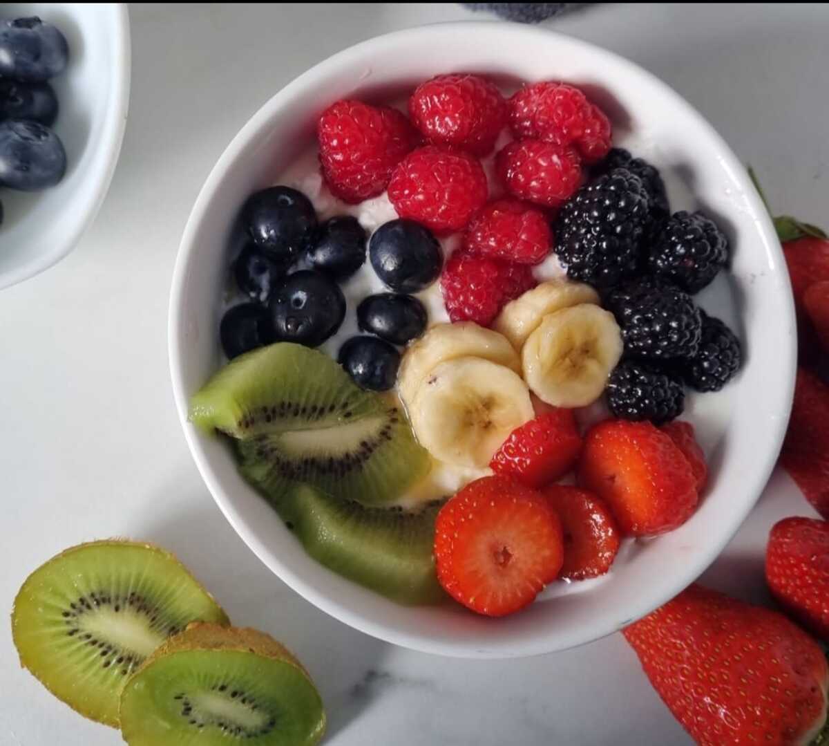 Bowl of cottage cheese topped with assorted fresh fruits.