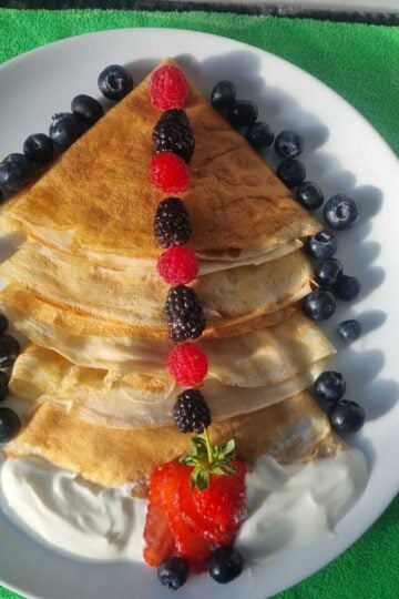 High-protein cottage cheese crepes folded on a plate, filled with creamy cottage cheese and topped with fresh berries.